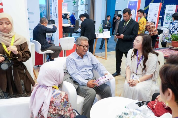 Indonesian Ambassador to Egypt looks at Shamrock medical latex gloves box presented by PT Haloni Jane Tbk Director at the Indonesian Pavilion during Africa Health ExCon 2026 in Cairo, featuring 'i was born from trees' brand display.